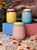 Three colorful steel tumblers with lids on a floral-patterned surface.