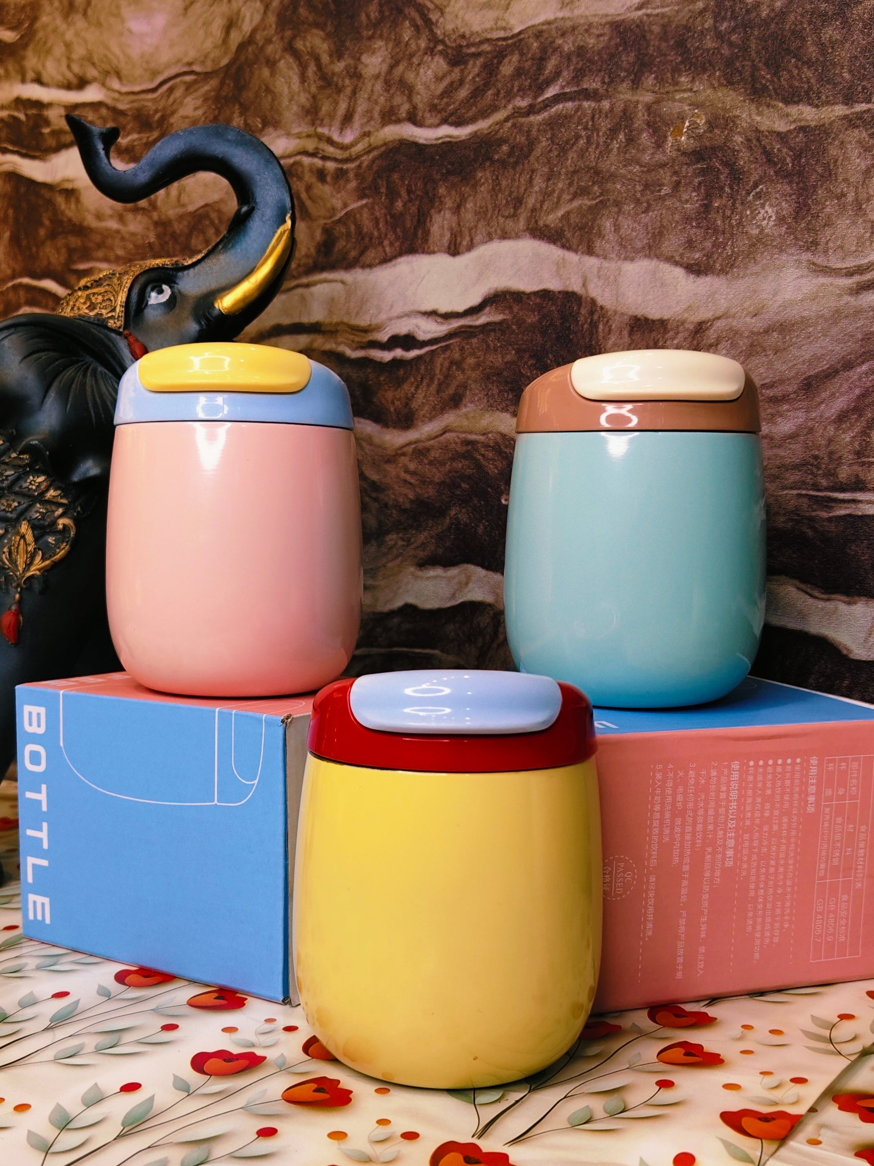 Three colorful steeltumblers on boxes with a decorative background