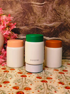 Three white containers with colored lids on a floral-patterned surface with a marble background