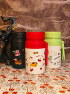 Three colorful thermos bottles or food jars with animal illustrations on a patterned surface.