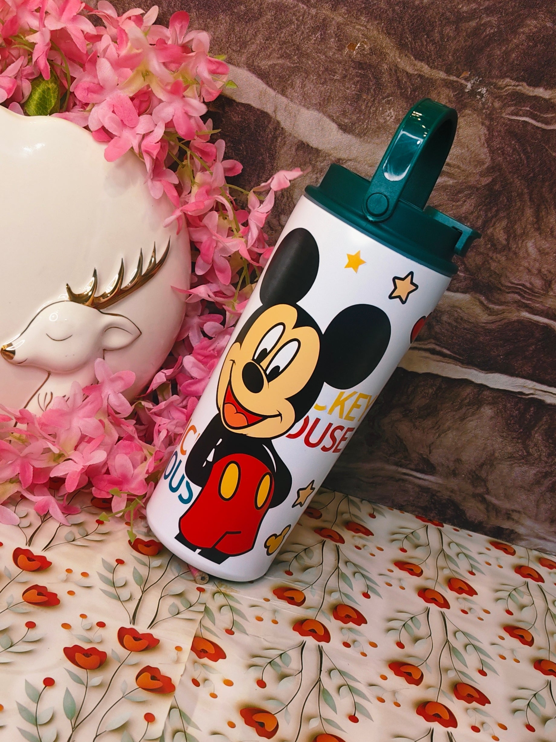 Mickey Mouse water bottle on a floral surface with decorative elements