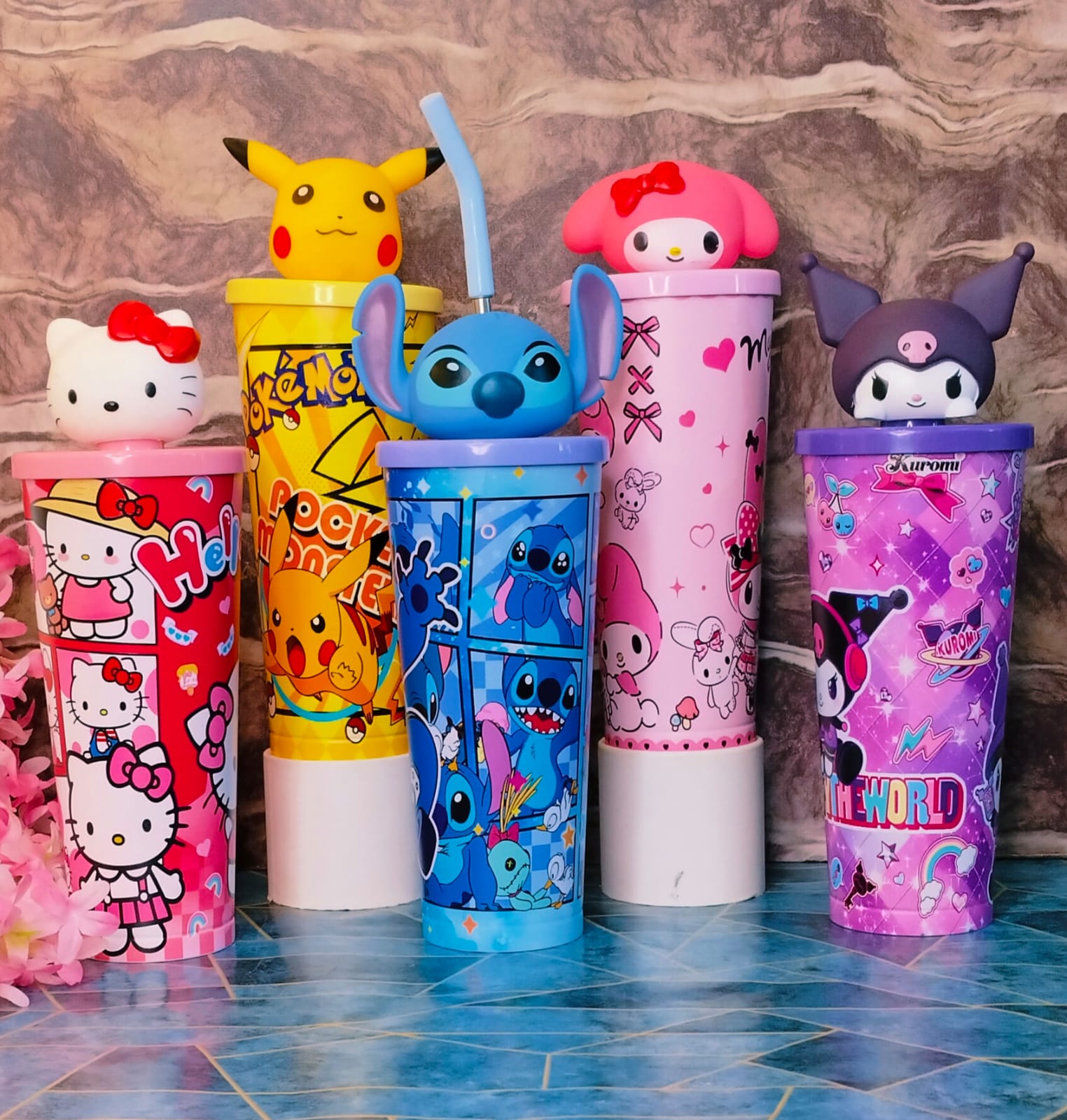 Set of colorful tumblers with cartoon character designs on a tiled floor.